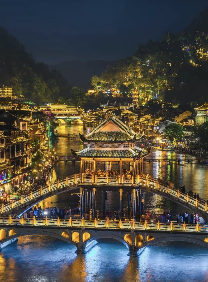 Fenghuang Ancient Town bridges and stilt houses lit by red lanterns over the Tuojiang River at night