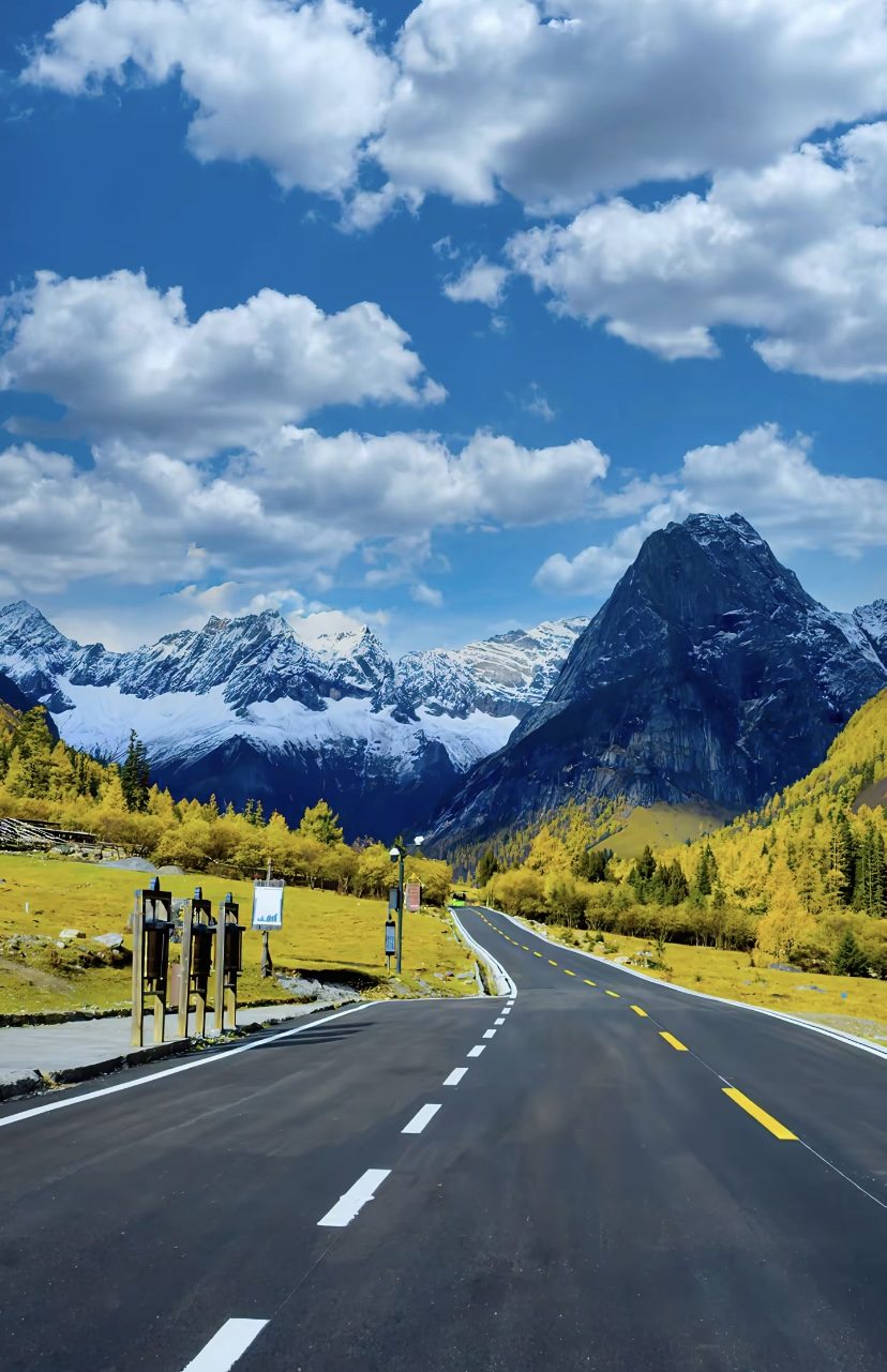 Mountain road and snow peaks with autumn larches in western Sichuan