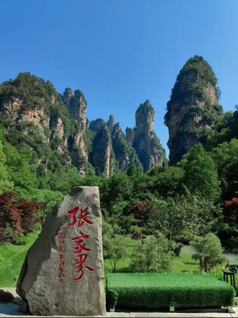Red calligraphy entrance stone at Zhangjiajie National Forest Park with sandstone pillars behind