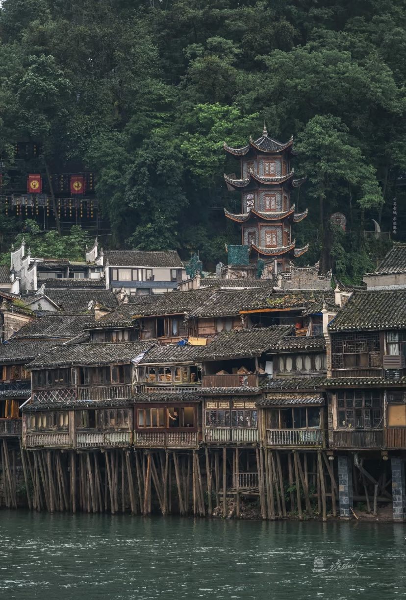 Stilted wooden diaojiaolou houses lining the Tuojiang River in Fenghuang Ancient Town by day