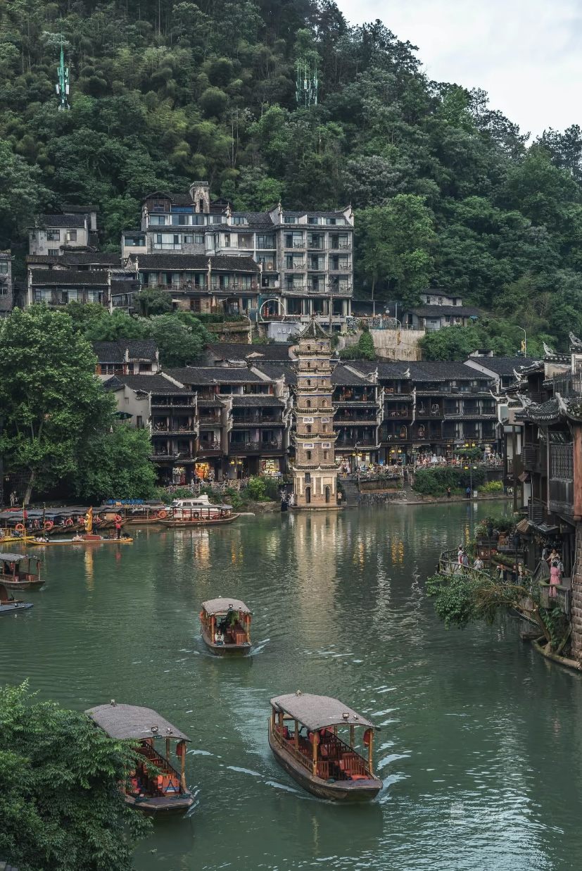 Stilted wooden diaojiaolou houses lining the Tuojiang River in Fenghuang Ancient Town by day