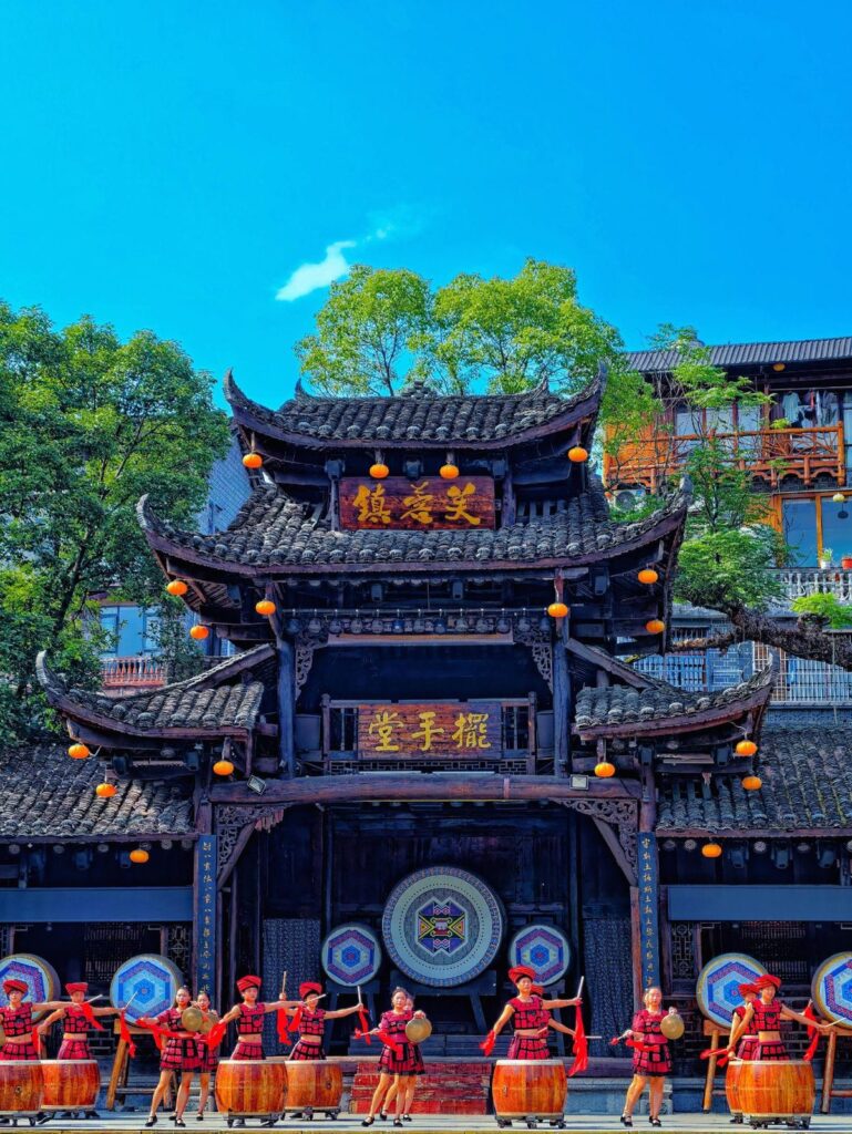 Tujia drum dancers performing in front of Baishou Hall in Furong Ancient Town