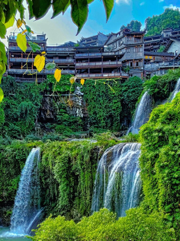 Furong Ancient Town waterfall below the stilt houses, with the town name carved into the cliff