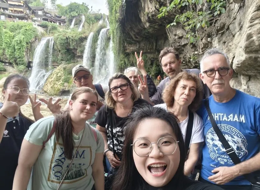 Our guide with overseas guests in front of the waterfall at Furong Town