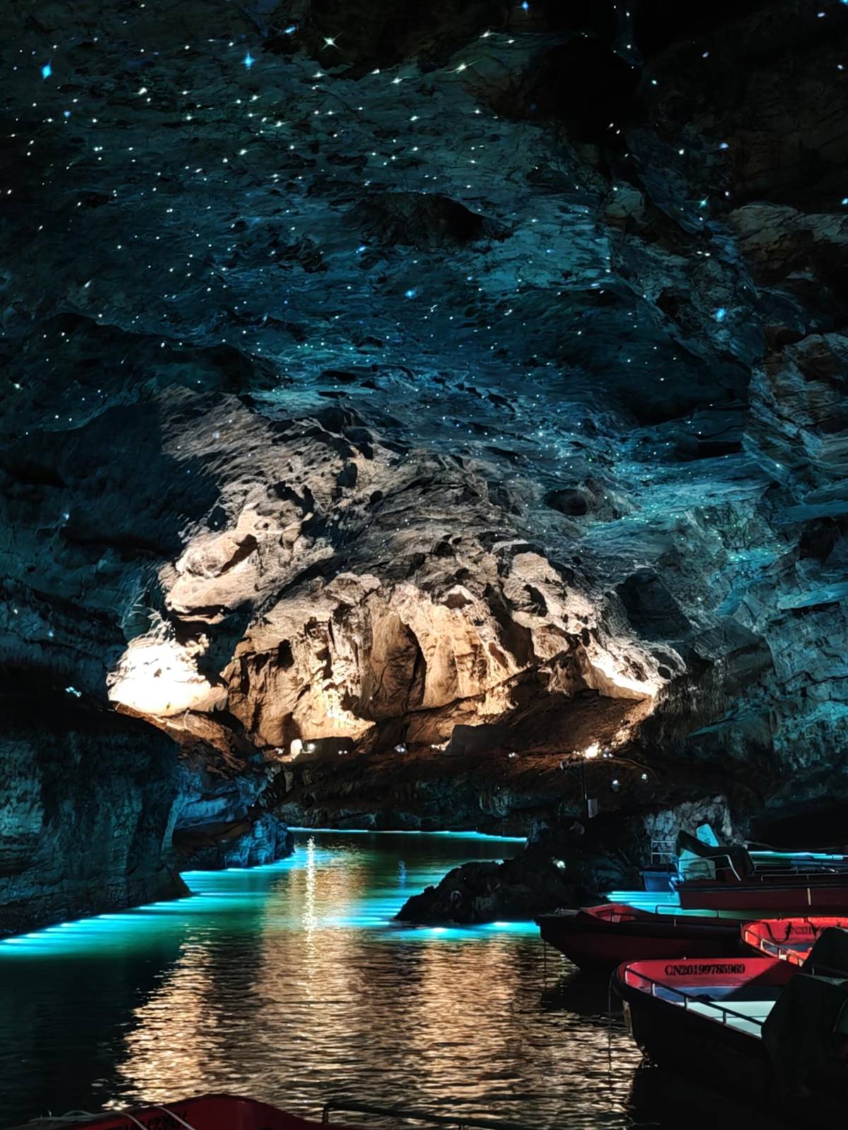 Boats moored at the Xiangshui River jetty inside Huanglong Cave, Zhangjiajie, under a ceiling lit with starlight-style lamps