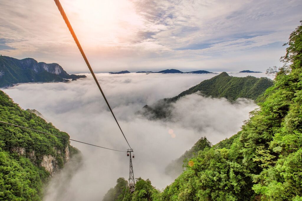 The Qixing Mountain cable car line above a sea of clouds, Zhangjiajie, with limestone peaks rising through the cloud