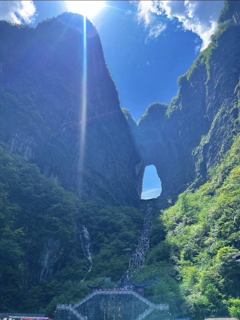 Visitors climbing the 999 steps to Tianmen Cave under a midday sun, Zhangjiajie