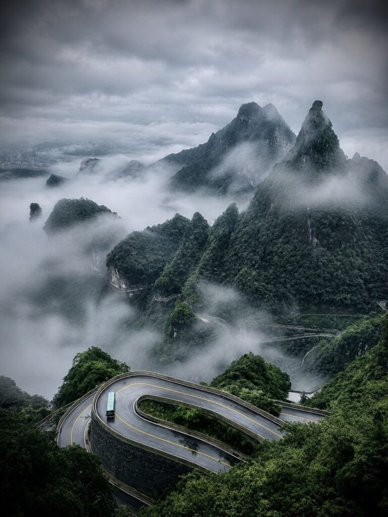 A bus on a hairpin bend of Tongtian Avenue, the 99-bend road up Tianmen Mountain, above a sea of cloud