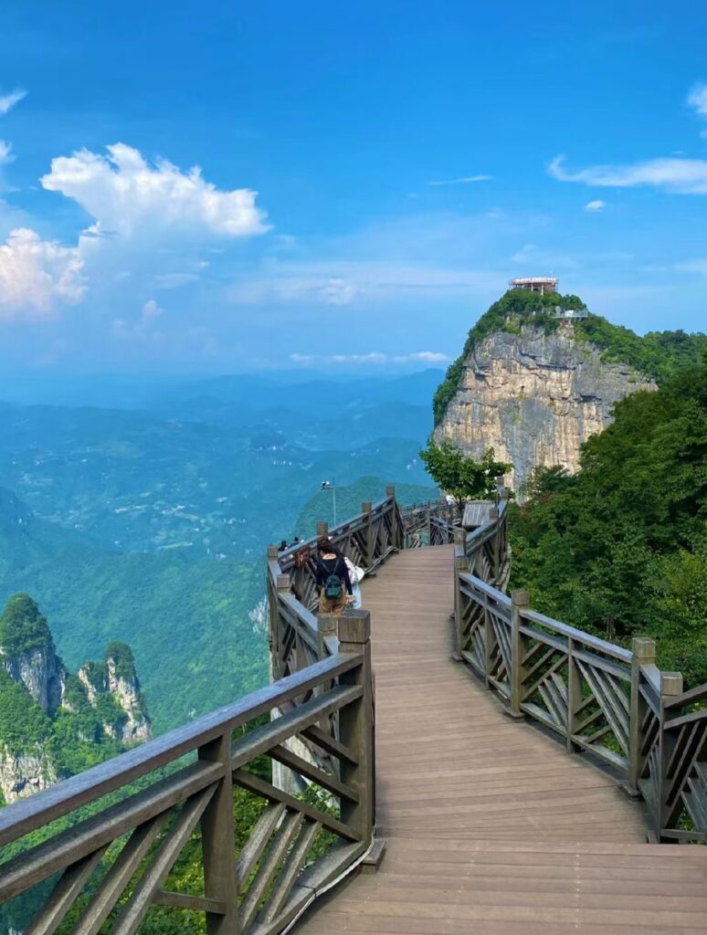 Wooden cliff-edge boardwalk on the summit of Tianmen Mountain, with a viewing platform on the peak ahead