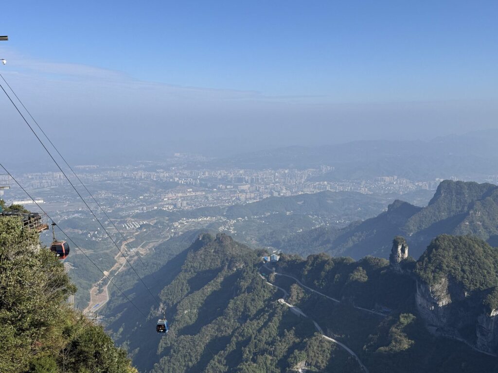View from the summit cliff edge of Tianmen Mountain over the cableway and the 99-bend road to Zhangjiajie city