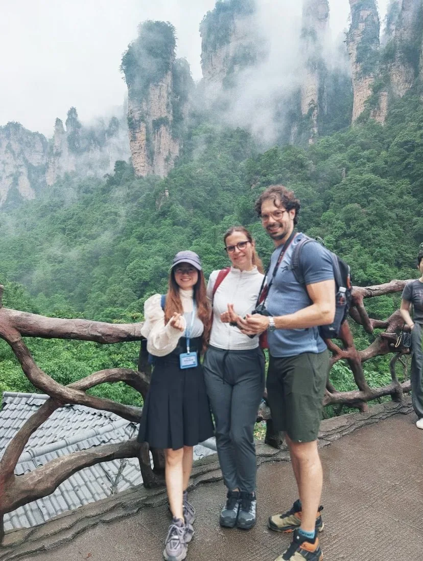 China Fantasy Travel guide with two overseas travellers at a misty Zhangjiajie viewpoint