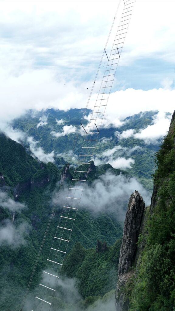 The Sky Ladder on Qixing Mountain, Zhangjiajie: a steel ladder climbing out from the cliff above a valley filled with cloud