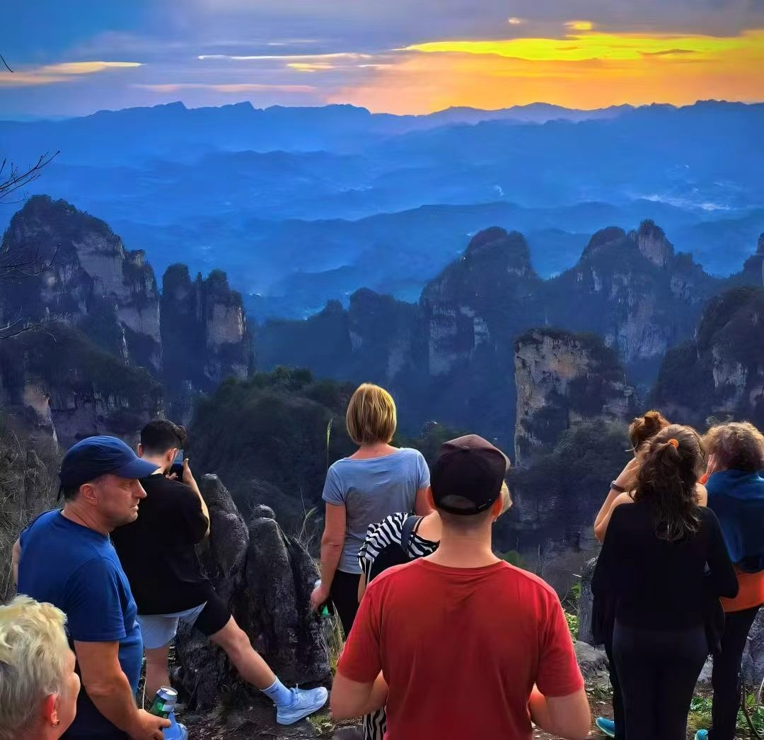 Overseas travellers watching the sunset from a mountain viewpoint in Zhangjiajie